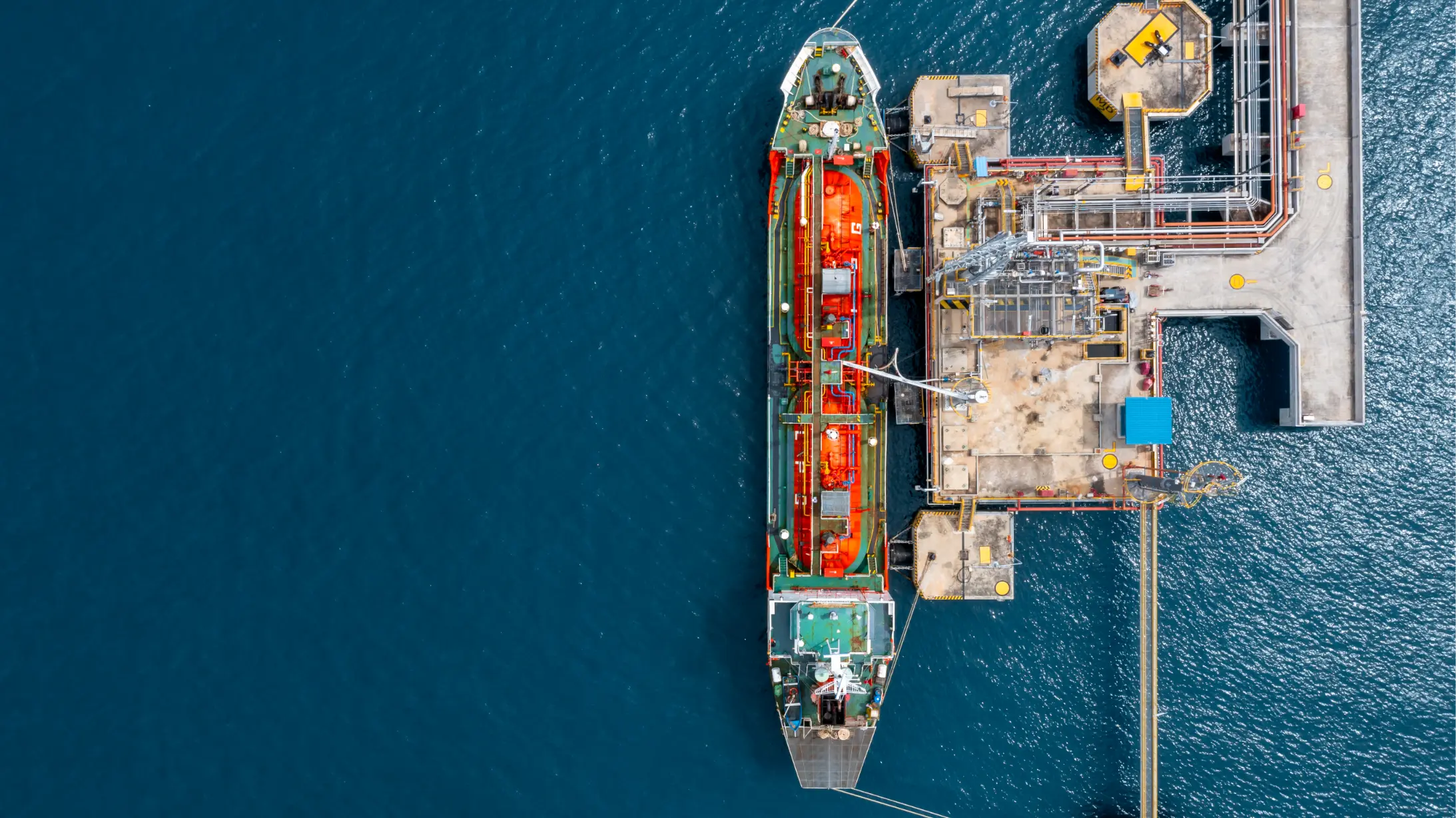Aerial view of an oil and gas tanker ship docked at a coastal oil depot terminal